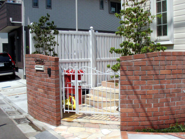 カーブ調のレンガ門柱に白い門扉を取り付けた世田谷区の外構工事施工例