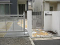 白い門柱の横に門扉の同じステンカラーのウィングゲートを設置した世田谷区の外構工事施工例