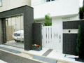 大田区のクローズ外構施工例/門柱とガレージには黒色ベースのタイルを貼り、白い門扉を組み合わせ、高級感あるどっしりとしたクローズ外構にした写真