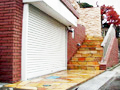 ブラウン色の壁材タイルと天然石貼りの床材を使用した高級感ある玄関入り口の大田区の外構工事施工例