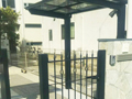 白い石貼りの門柱に黒い鋳物門扉を組み合わせた外構工事の施工例