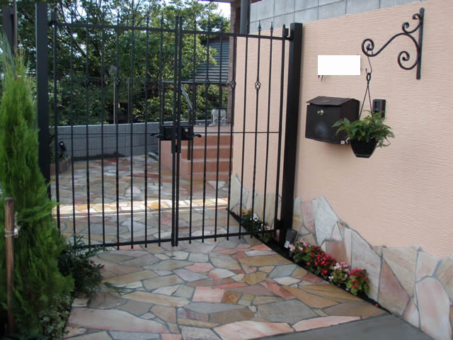 大田区での外構工事施工例│ピンク系ジョリパッド仕上げの塀と、下部に天然石を貼り合わせた門まわりデザイン